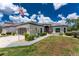 Beautiful single-story home with a gray driveway, tropical foliage, and a charming entryway at 26254 Stillwater Cir, Punta Gorda, FL 33955