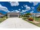 Attached two-car garage with a paved driveway, lush green grass, and manicured landscaping at 26254 Stillwater Cir, Punta Gorda, FL 33955