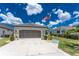 Attached two-car garage with a paved driveway and manicured landscaping under a bright blue sky at 26254 Stillwater Cir, Punta Gorda, FL 33955