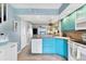 Open kitchen with turquoise cabinets, modern appliances, and convenient access to the living area at 26310 Rampart Blvd # 504, Punta Gorda, FL 33983