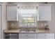 Close-up view of the kitchen sink area, featuring granite countertops and bright window view of the outdoors at 2736 Suncoast Lakes Blvd, Punta Gorda, FL 33980
