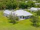 Lush trees surround the well-kept lawn and newly built home, with an outdoor living space and metal roof at 28960 Gin Ln, Punta Gorda, FL 33982