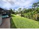Expansive back yard with a screened-in pool, dock, and lush tropical foliage at 319 Kindred Blvd, Port Charlotte, FL 33954
