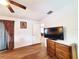 Bedroom with light wood floor, a ceiling fan, dresser, and large flat screen television at 3456 Highlands Rd, Punta Gorda, FL 33983