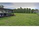 Expansive backyard with green grass, mature landscaping and an enclosed patio at 3512 Nekoosa St, North Port, FL 34287