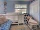 Comfortable bedroom showcasing a crib, rocking chair and storage, and a window with natural light at 3512 Nekoosa St, North Port, FL 34287
