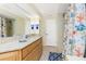 Light bathroom features granite counters, wood cabinets and shower with colorful decorative curtain at 4051 Rock Creek Dr, Port Charlotte, FL 33948