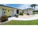 Close-up of a home's entrance featuring a bright yellow front door, lush landscaping, and a well-maintained lawn at 4051 Rock Creek Dr, Port Charlotte, FL 33948