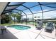 The screened lanai has a waterfront kidney shaped pool with lounge chairs for relaxing at 4051 Rock Creek Dr, Port Charlotte, FL 33948