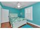 Bright blue bedroom with shutters, floral bedding, ceiling fan, and hardwood floors at 415 W Marion Ave, Punta Gorda, FL 33950