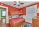 Red bedroom features a wooden bunk bed, ceiling fan, and natural light from window at 415 W Marion Ave, Punta Gorda, FL 33950