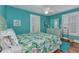 Bright blue bedroom with shutters, floral bedding, dresser, and ceiling fan at 415 W Marion Ave, Punta Gorda, FL 33950