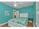 Bright bedroom with aqua walls, ceiling fan, and white bed with tropical print comforter at 415 W Marion Ave, Punta Gorda, FL 33950