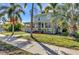 Inviting two-story home with mature palm trees, a brick walkway, and a charming front porch at 415 W Marion Ave, Punta Gorda, FL 33950