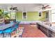 Enclosed porch featuring a dining table, seating area, brick flooring, and two ceiling fans at 415 W Marion Ave, Punta Gorda, FL 33950