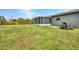 Expansive backyard featuring a screened lanai, lush lawn, tropical foliage, and a convenient riding lawn mower at 457 Glenridge Nw Ave, Port Charlotte, FL 33952