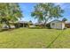 Spacious backyard with mature trees, storage shed, screened patio, and lush greenery, perfect for relaxation at 496 Fletcher St, Port Charlotte, FL 33954