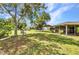 View of the property's expansive backyard with a storage shed, seating, mature trees, and a screened patio at 496 Fletcher St, Port Charlotte, FL 33954