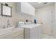 Well-lit laundry room with white washer and dryer, sink, cabinetry, and decorative mirror for functional appeal at 531 Madrid Blvd, Punta Gorda, FL 33950