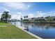 Lovely canal front with lush green grass, concrete seawall, boat dock, and tropical palm trees at 531 Madrid Blvd, Punta Gorda, FL 33950