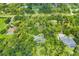 Aerial view of a home with lush greenery, a pool, and a pond nearby, surrounded by mature trees at 6514 N Biscayne Dr, North Port, FL 34291