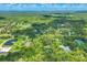 Expansive aerial view featuring lush green landscapes, mature trees, and scattered residential properties in the distance at 6514 N Biscayne Dr, North Port, FL 34291