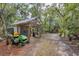 Outdoor backyard shed with a green lawnmower parked in front of it, surrounded by mature trees at 6514 N Biscayne Dr, North Port, FL 34291