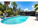 Sparkling in-ground pool with mature palms and screen enclosure under a bright blue sky at 8513 Heister St, Punta Gorda, FL 33982