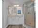 White bathroom with glass enclosed shower, marble counter top, and a large vanity mirror at 900 E Marion Ave # 1203, Punta Gorda, FL 33950