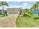 Inviting single-story home with manicured lawn, brick driveway, and a charming facade with tropical accents at 10478 Coquina Ct, Placida, FL 33946