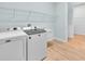 Bright laundry room featuring Maytag washer and dryer, storage shelves and wood-look flooring at 10478 Coquina Ct, Placida, FL 33946