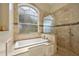 Modern soaking tub with an arched window and separate glassed shower at 1323 Mineo Dr, Punta Gorda, FL 33950