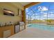 Outdoor kitchen featuring a grill, sink, and refrigerator by the screened-in pool at 1323 Mineo Dr, Punta Gorda, FL 33950