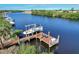 Scenic aerial view of a private dock with a boat, waterfront seating, and access to serene waterways, with lush greenery surrounding at 14436 Ponce De Leon Trl, Port Charlotte, FL 33981