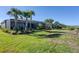 Landscaped backyard showcases lush green grass, palm trees, and a screened lanai with a private dock leading to the waterway at 14436 Ponce De Leon Trl, Port Charlotte, FL 33981