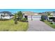 Beautiful single-story home featuring a lush lawn, tropical landscaping, and a brick paver driveway at 14436 Ponce De Leon Trl, Port Charlotte, FL 33981