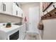 Bright laundry room with white cabinets, modern appliances, and hooks for extra storage at 14436 Ponce De Leon Trl, Port Charlotte, FL 33981