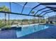 Inviting screened-in pool with a spa and brick-paved deck surrounded by lush landscaping at 14436 Ponce De Leon Trl, Port Charlotte, FL 33981