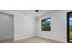 Bright bedroom features wood-look flooring, contemporary lighting fixture and a window looking out onto a green landscape at 17156 Eugene Ave, Port Charlotte, FL 33954