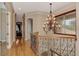 Hallway with hardwood floors, decorative wrought iron railing, and chandelier lighting at 17509 Ohara Dr, Port Charlotte, FL 33948