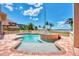A uniquely shaped backyard pool and spa are surrounded by a brick patio and lush landscaping with waterfront views at 17509 Ohara Dr, Port Charlotte, FL 33948
