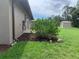 Backyard exterior with a large bush near the home and a metal storage shed in the far background at 18094 Ackerman Ave, Port Charlotte, FL 33948