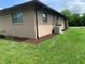 The exterior of the property features brown mulch along the foundation, grass, and an AC unit near the back at 18094 Ackerman Ave, Port Charlotte, FL 33948