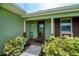 Charming front porch with a decorative glass door, a welcoming sitting area, and lush landscaping for added curb appeal at 21539 Gladis Ave, Port Charlotte, FL 33952