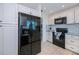 Eat-in kitchen showcases a black refrigerator with stainless steel appliances and white cabinets at 21539 Gladis Ave, Port Charlotte, FL 33952