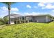 Large backyard with a palm tree, screened-in pool area, and green grass at 2309 Conway Blvd, Port Charlotte, FL 33952