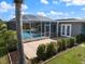 A screened pool with a brick patio and well-manicured shrubbery and a view of the back of the house at 2309 Conway Blvd, Port Charlotte, FL 33952