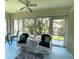 Cozy sunroom featuring comfortable seating, a ceiling fan, and multiple large windows offering views of the surrounding greenery at 24132 Buckingham Way, Punta Gorda, FL 33980