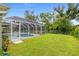 View of the screened-in pool area in the backyard featuring lounge chairs and well-maintained landscaping at 2455 Jacoby Cir, North Port, FL 34288