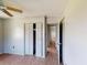 This bedroom features a ceiling fan, wood-look floors, closet, and an open doorway to the bathroom at 2513 Ambrose Ln, Port Charlotte, FL 33952